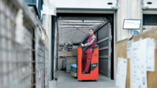 Bediener fährt mit Niederhubwagen T14 von Linde MH von der Lkw-Ladefläche