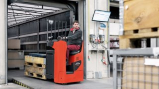 Bediener fährt mit Niederhubwagen T20 von Linde MH von der Lkw-Ladefläche