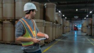 Interaktive Warnweste von Linde Material Handling sorg für mehr Sicherheit Lagerarbeiter trägt die interaktive Warnweste von Linde Material Handling im dunklen Lager