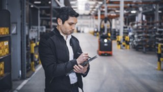 Ein Linde Material Handling Mitarbeiter steht im Lager und macht sich Notizen auf seinem Tablet.
