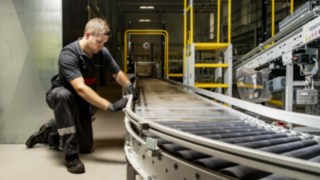 Ein Servicetechniker von Linde MH repariert eine Rollenbahn