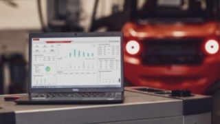 Fleet Dashboard des Linde Warehouse Managers auf einem Laptop-Bildschirm, ein Gabelstapler im Hintergrund