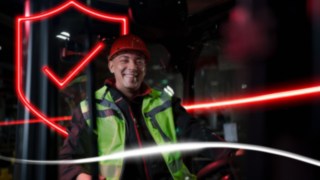 Person mit Arbeitskleidung und Schutzhelm sitz in einem Linde Stapler