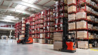 Schmalgangstapler Linde K-Modular und Schubmaststapler Linde R14 vor einem Palettenregal 