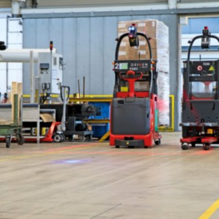 Zwei automatische Hochhubwagen L-MATIC transportieren Waren zwischen Verpackungslinie und Durchlauflager.