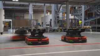 Drei Autonome Mobile Roboter (AMR) von Linde MH fahren durch das Lager Drei Autonome Mobile Roboter (AMR) von Linde MH fahren durch das Lager