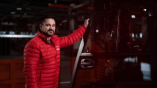 Mitarbeiter von Linde Material Handling steht neben einem Flurförderzeug und lächelt in die Kamera.