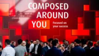 Messewand mit dem Slogan "Composed around you"