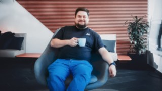 Ein Mitarbeiter entspannt mit Kaffeetasse in der Hand auf einem Sessel und steht für gelebte Work-Life-Balance sowie ein positives Arbeitsumfeld bei KION Automation.