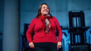 Eine Mitarbeiterin aus dem Vertrieb steht selbstbewusst vor einer Reihe moderner Linde-Flurförderzeuge, was Kundennähe, Begeisterung für innovative Lösungen und die globale Wirkung erfolgreicher Vertriebsarbeit symbolisiert. 