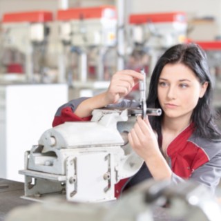 Auszubildende bei Linde Material Handling stehen vor einem Gabelstapler Auszubildende von Linde Material Handling arbeitet an Werkbank mit Messschieber in der Hand